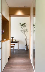 A minimalist modern home office features sleek, minimalist furniture, concrete floor, and tall plant in planter.