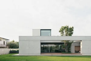 Modern residential exterior featuring a minimalist design with concrete and glass materials.