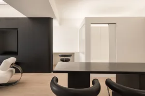 A minimalist residential interior with black and white furniture and wooden elements.