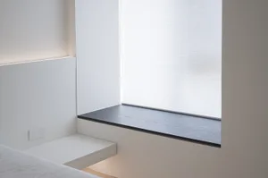 Minimalist bedroom featuring a floating shelf against a white wall.