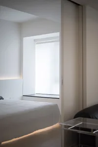 A minimalist bedroom with a white bed and walls