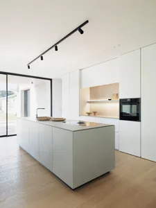 Minimalist kitchen with concrete island and white cabinets.