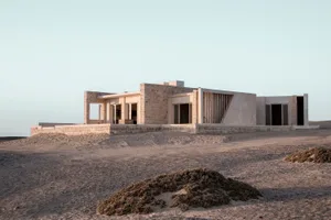 Modern residential building with minimalist design featuring stone and concrete materials.