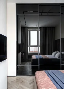 Modern bedroom featuring wooden flooring and metal headboard.