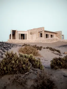 A modern residential house constructed with stone materials, featuring large windows and an open, airy design.