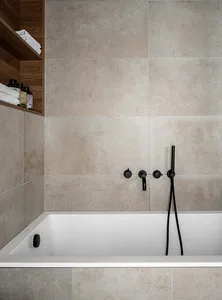 A modern minimalist bathroom with beige tile walls and a white bathtub.