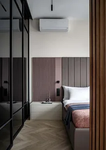 A minimalist bedroom featuring a upholstered bed frame, wood flooring, and metal accents.