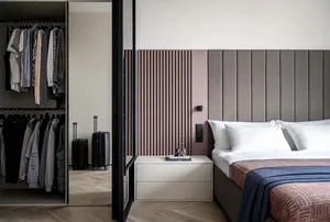 A minimalist bedroom with a gray upholstered headboard and a walk-in closet.