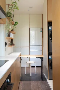 A minimalist kitchen with white laminate countertops, wooden cabinets, and metal appliances.