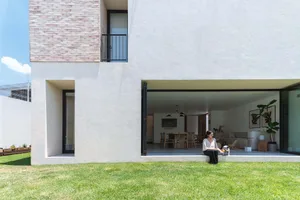 A minimalist white modern house with a concrete exterior and a neatly maintained garden.