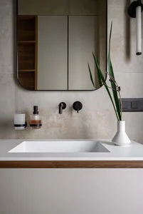 A modern bathroom featuring a floating sink with a white basin and a wooden countertop, set against a concrete and wood wall 