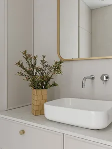 A modern bathroom sink with decorative elements and a vase of flowers.