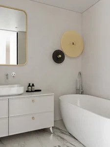 Modern bathroom with white ceramic tub, sink, and cabinet with gold accents.