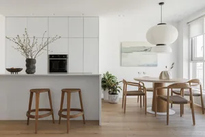 Modern dining room featuring white marble surfaces and wooden furniture.