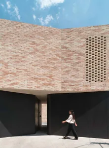 A modern exterior building made of brick with a person walking in front of it.