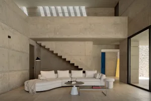 A modern interior living room with minimalist design, concrete walls, and a white sectional sofa.