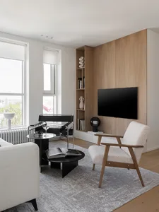 A modern minimalist living room with white furniture, a black coffee table, and a large window.