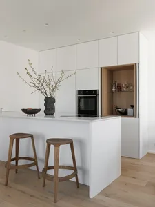 Modern white kitchen with minimalist design and wooden stools