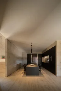 A modern, minimalist kitchen with concrete walls and black metal accents.