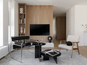 Modern living room with black chairs, wooden shelves, and a metal accent table.