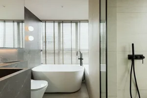 Modern minimalist bathroom featuring a white bathtub, terrazzo tiles, and a white toilet.