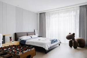 A minimalist bedroom featuring wooden furniture and a large window with sheer curtains.