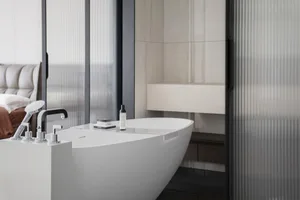 White minimalist bathroom with a freestanding concrete bathtub, chromed fixtures, and a floating vanity.