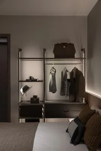 Modern bedroom featuring a metal storage unit with clothing, hats, and other items arranged neatly.