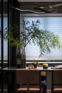 A modern dining room featuring a glass centerpiece vase with greenery.