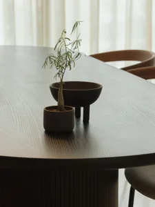 A modern table setting with a wooden table and a small plant in a decorative pot.
