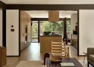 Contemporary kitchen and living space with wooden accents and a view of greenery.