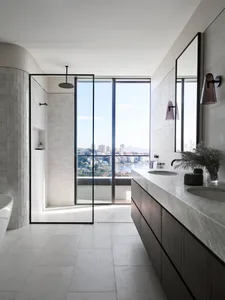 A modern minimalist bathroom featuring marble flooring, a glass-enclosed shower, and expansive windows overlooking a cityscap