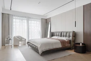 Modern minimalist bedroom with a leather bed and fabric headboard, featuring large windows with sheer curtains and a sleek si