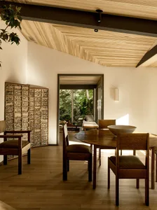 Modern minimalist living room featuring wooden furniture and walls, with a view of a garden through large windows.
