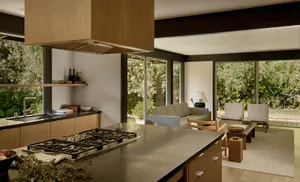 Modern residential kitchen with a wooden and oval-trafalged design featuring a central island with a stove, open shelving, an