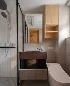 A minimalist bathroom features concrete countertops and a wooden cabinet.
