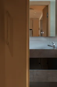 Contemporary bathroom interior featuring a concrete countertop with a sleek faucet and a mirror reflecting the ceiling.