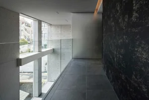 A modern interior corridor featuring a minimalist design with concrete walls and flooring.