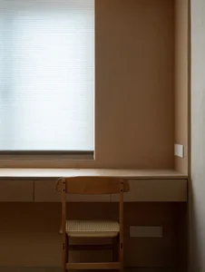 A modern workstation with a wooden chair and table, featuring a window with blinds.