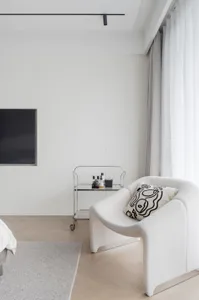 Modern minimalist bedroom with a textured fabric armchair.