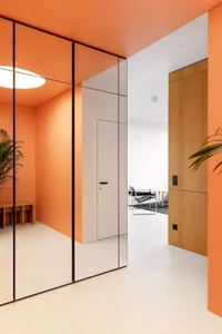 Modern minimalist interior with orange accent walls and wooden furniture.