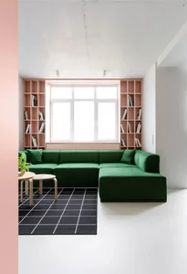 Minimalist living room with a green sofa, bookshelf, and modern furniture