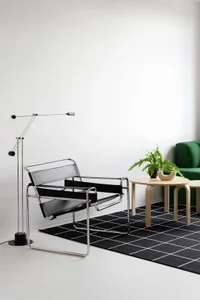 A modern living room featuring a black leather armchair, a round wooden coffee table with a green plant, and a black and whit