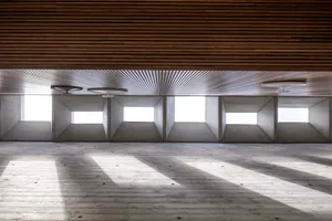 Modern interior with concrete walls and floors, featuring geometric shapes and large windows.