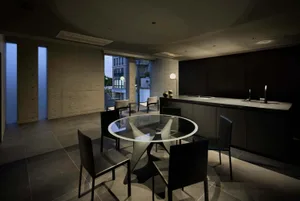 Modern kitchen and dining area with dark wood, concrete, and glass materials.