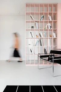A contemporary library with metallic shelving and a black chair on a white speckled floor.