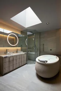 Modern master bathroom suite featuring a ceramic tile floor, freestanding tub, glass shower enclosure, and double vanity with