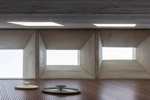 A modern office with exposed concrete ceilings and geometric light fixtures.