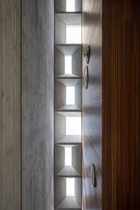 A modern interior with concrete walls and wooden elements, featuring cut-out spaces and geometric shapes.