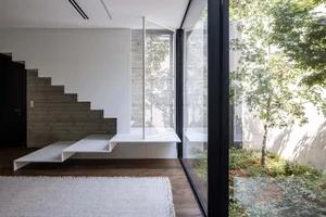 Modern minimalist living room featuring white concrete and wood finishes.